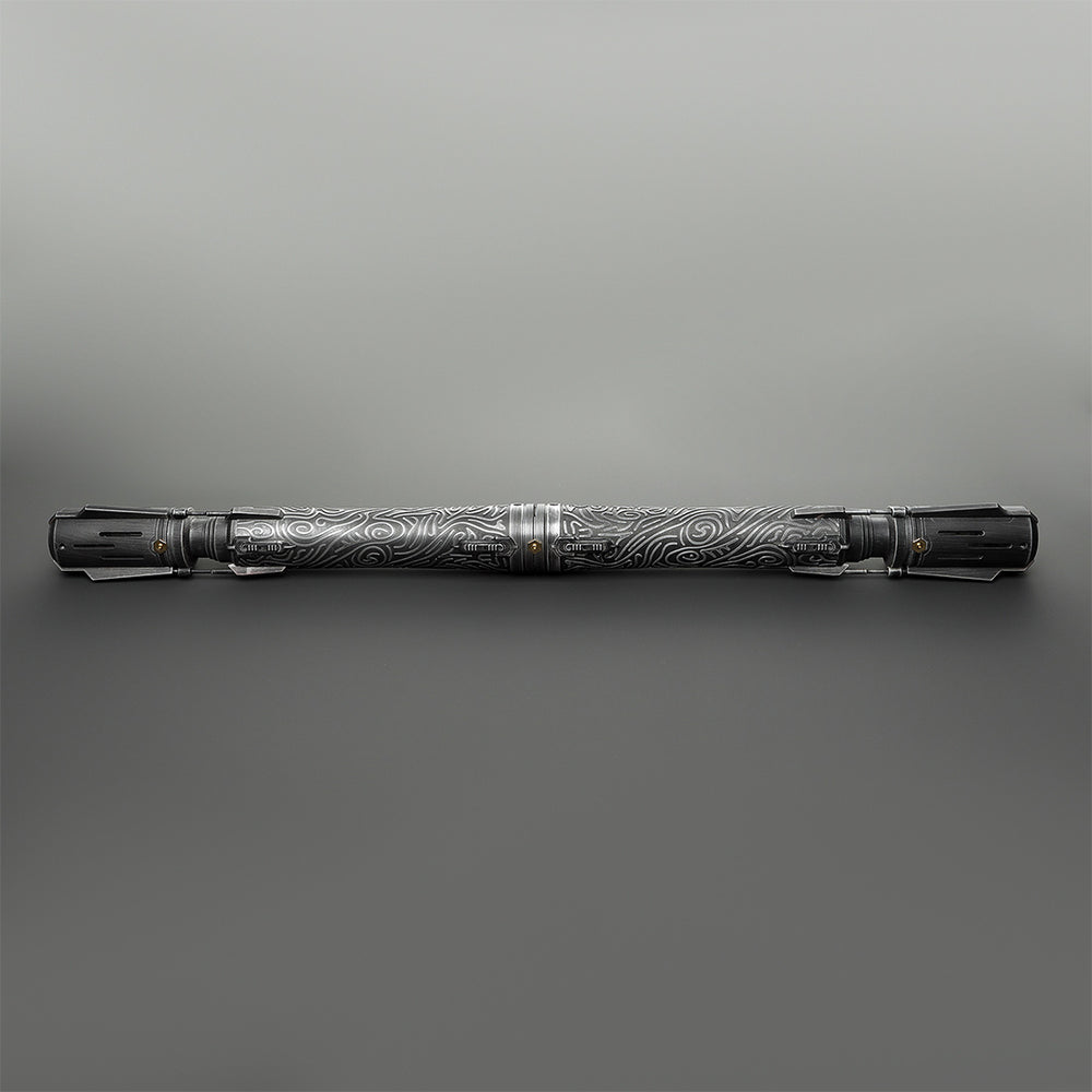 A long, cylindrical metallic tool or accessory with engraved swirling patterns, shown horizontally against a smooth gray gradient background.