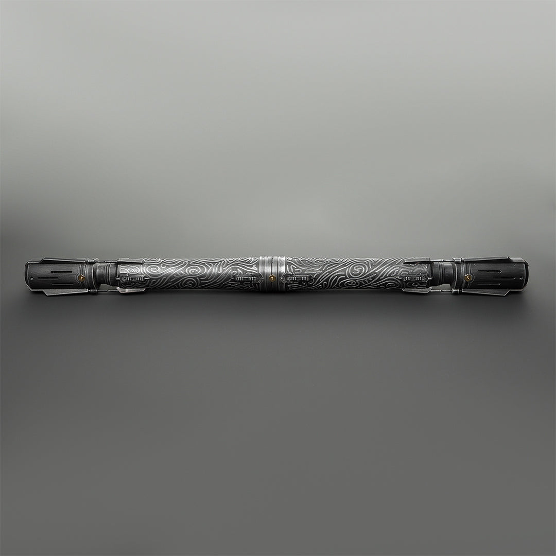 A long, cylindrical metallic tool or accessory with engraved swirling patterns, shown horizontally against a smooth gray gradient background.